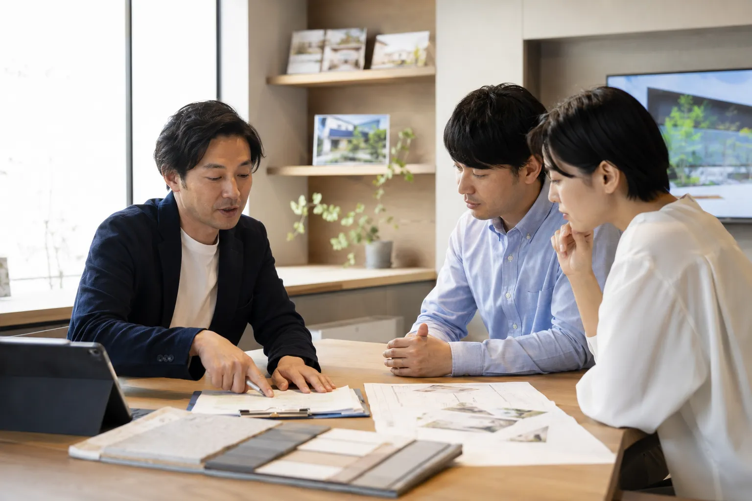 外構工事の見積書や図面を見ながら内容を説明する外構プランナーと日本人夫婦