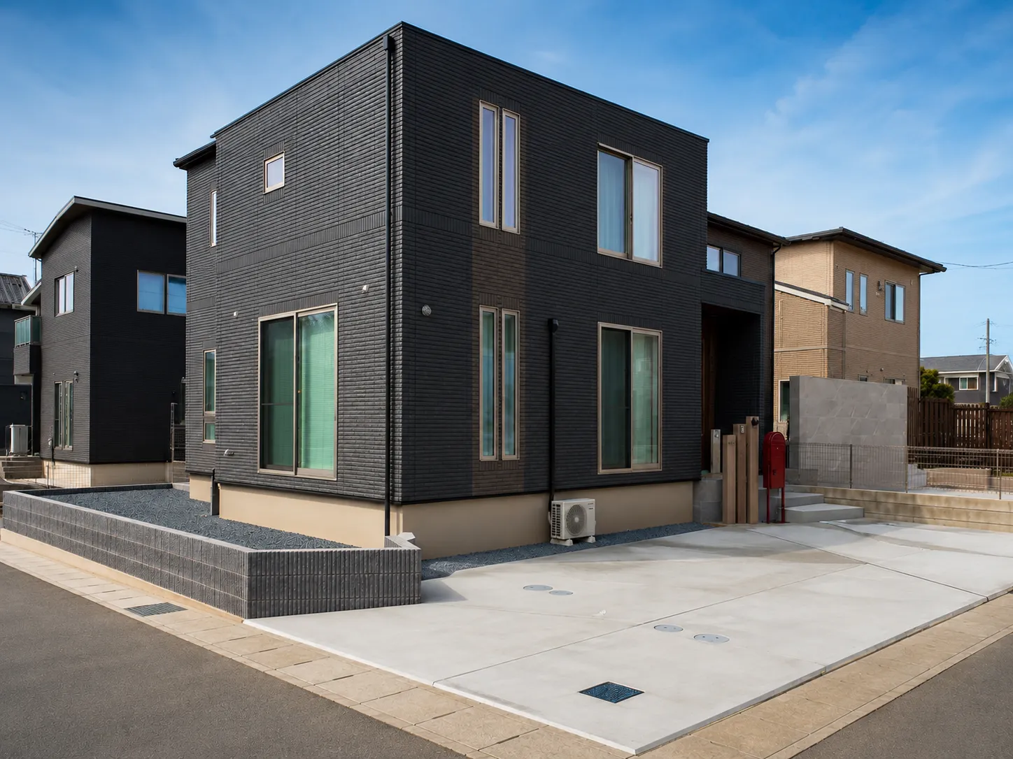 印西市のシンプルモダン外構。ブラックの住宅と広々とした土間コンクリート、アプローチを撮影した全景写真。